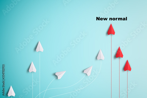 White paper plane flying towards the red paper plane and to head into new normal way. COVID 19 change a lifestyle and business a new way of life concept. photo