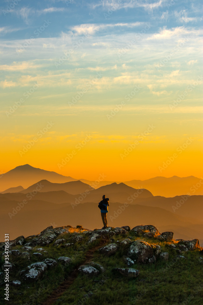 Homem montanhista apreciando o nascer do sol sobre as montanhas