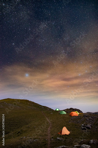 Noite estrelada com barracas de camping sobre as montanhas photo