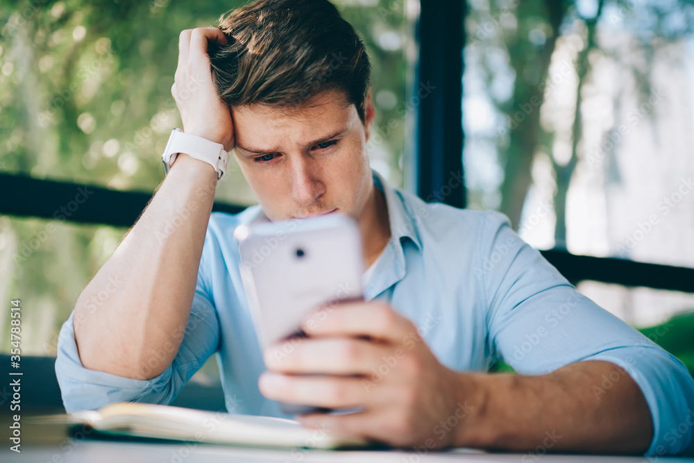 Fototapeta premium Thoughtful hipster blogger updating profile on telephone