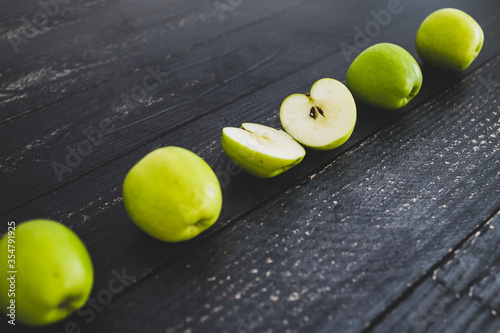 food ingredients concept  green apples ined up on wooden table with some cut in half