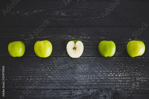 food ingredients concept, green apples ined up on wooden table with some cut in half photo