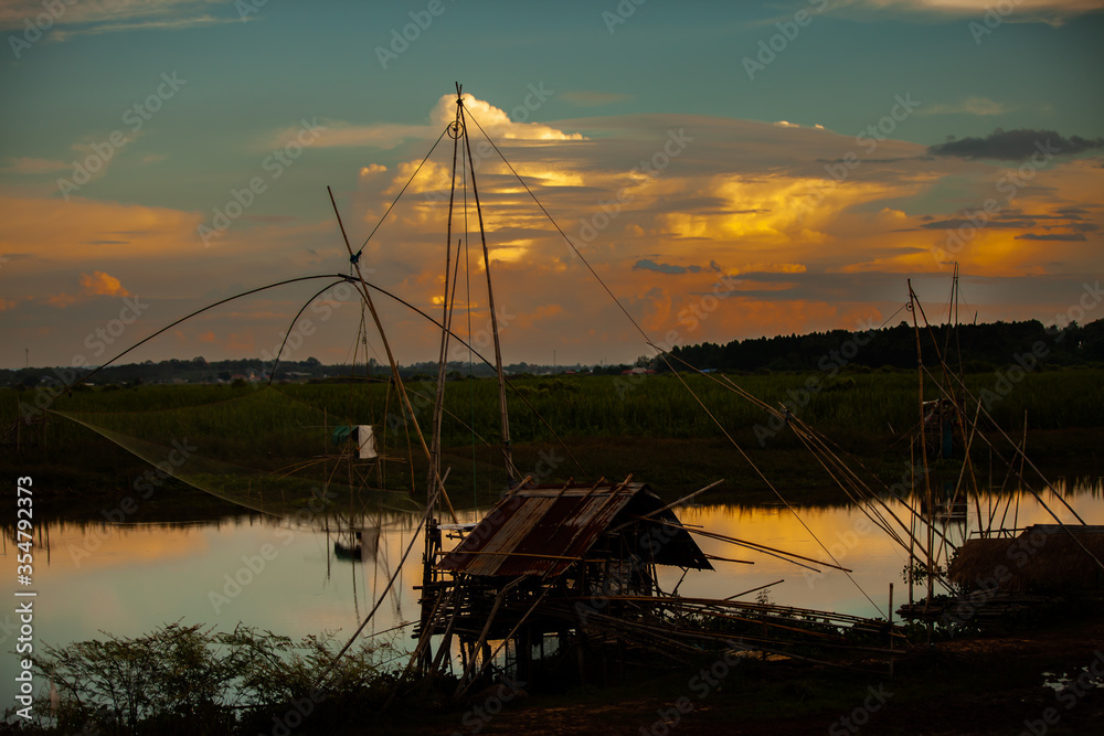 Traditional fishing tool or bamboo fish trap on sunset light, landscape silhouette.