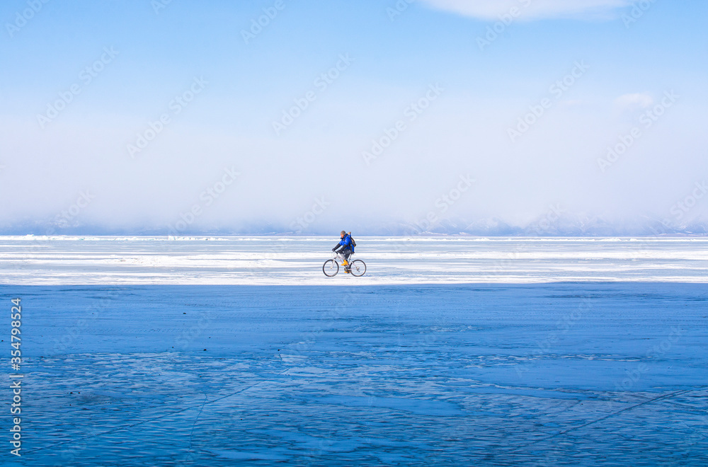 A man doing solo outdoor activity, enjoying time alone in nature, riding a bicycle on frozen lake in winter, wide angle image A man doing solo outdoor activity, enjoying time alone in nature, riding a bicycle on frozen lake in winter, wide angle image