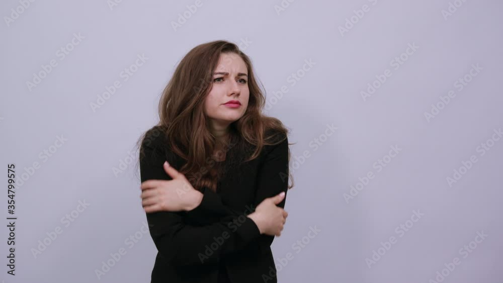 Hugging herself to warm while feeling cold arms crossed fear expression on face loneliness and depression. Being terrified with unknown sound. Young attractive woman brunette in a black t-shirt Hugging herself to warm while feeling cold arms crossed fear expression on face loneliness and depression. Being terrified with unknown sound. Young attractive woman brunette in a black t-shirt