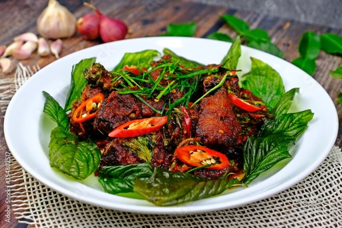 Stir fried crispy catfish with red chili paste surrounded by crispy Thai basil.