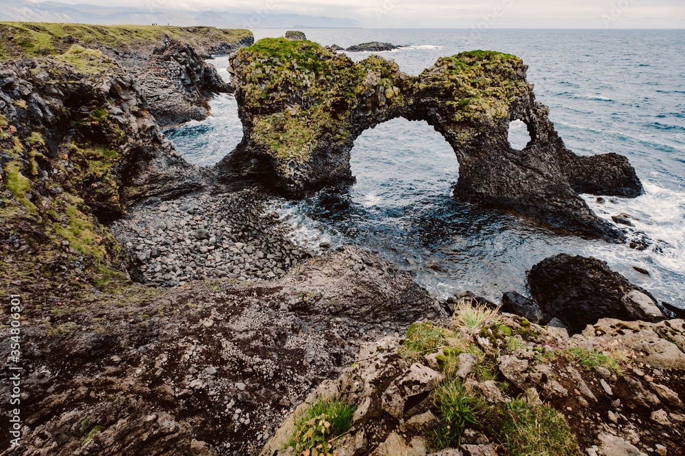 Amazing seascape, Gatklettur basalt rock arch at the volcanic cliff, Atlantic coast of Arnarstapi in the west of Iceland, natural background. Postcard concept. Rocks and stones with abstract forms.