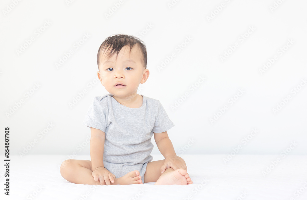 Happiness and smiling baby boy sitting on bed and looking at camera, kids playing concept