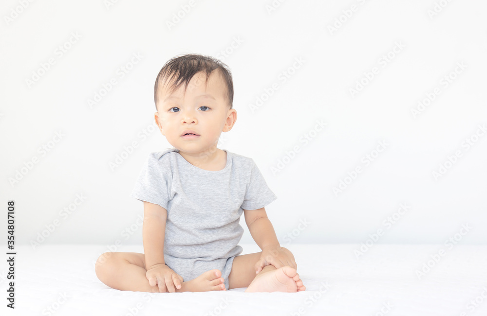 Happiness and smiling baby boy sitting on bed and looking at camera, kids playing concept Happiness and smiling baby boy sitting on bed and looking at camera, kids playing concept