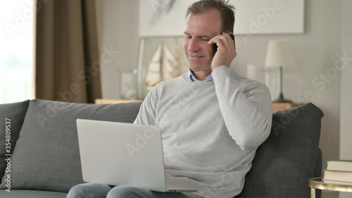 Wallpaper Mural Cheerful Middle Aged Businessman talking on Smartphone on Sofa Torontodigital.ca