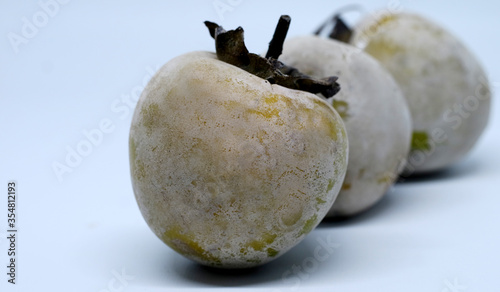 Persimmon or kesemek on white background. The fruit is covered by white flour after immersing in water with calcium oxide to remove tannin.
 photo
