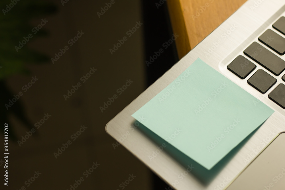 Closeup of note pad is to remind you of a blue note and paste it on the keyboard of the laptop computer which has a grey colour and there is space for the left thread of the image Closeup of note pad is to remind you of a blue note and paste it on the keyboard of the laptop computer which has a grey colour and there is space for the left thread of the image