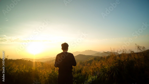 Back view silhouette of young tourist traveler man standing with beautiful morning sunrise of Elephant Hills National Park (Noen Chang Suek) at Thong Pha Phum, Kanchanaburi , Thailand © HarryKiiM Stock