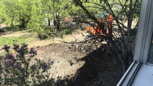 Repair work in the courtyard of an apartment building. Excavator removes road surface