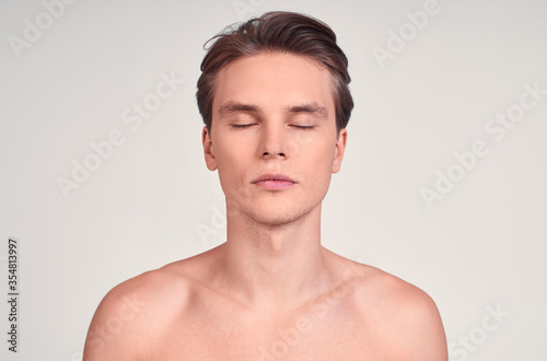 Portrait of a young sexy naked white guy with closed eyes.