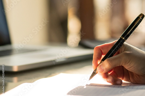Hand of businesswoman writing on paper in office. Writing notes and planning her schedule.