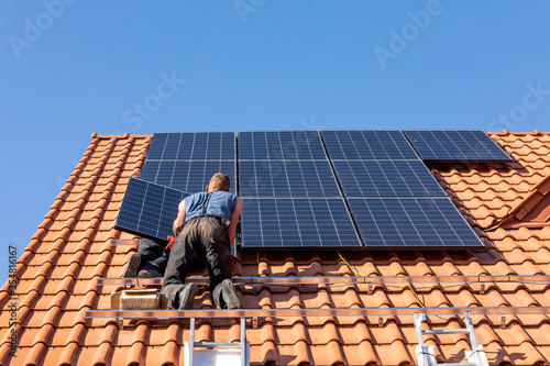  Workers installing solar electric panels on a house roof in  Ochojno. Poland