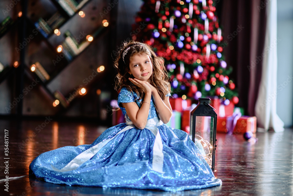 Cute little girl laying on flor with bright christmas garland in her hair.