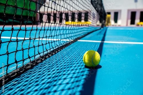 The yellow tennis ball on the blue hard court and the outdoor black net  S © supachai
