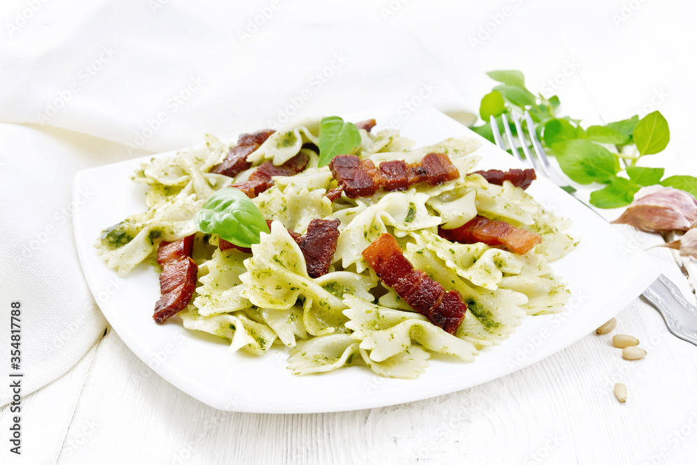 Farfalle with pesto and bacon in plate on white board