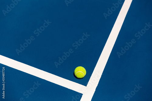 The yellow tennis ball on the blue hard court and the outdoor black net  S © supachai
