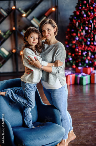 Mother and Child Hug in Front of a Christmas Tree.