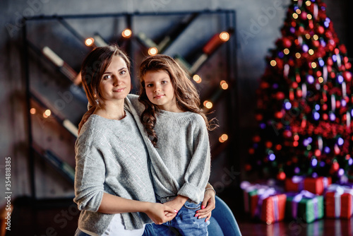 Mother and Child Hug in Front of a Christmas Tree.