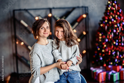 Mother and Child Hug in Front of a Christmas Tree.