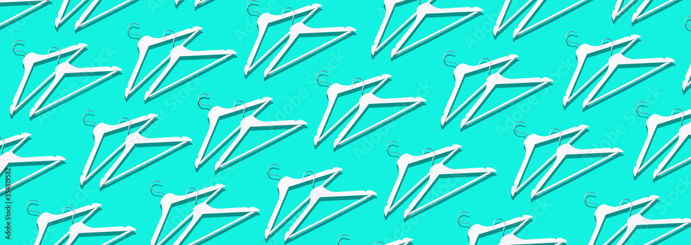 Top view of white clothes hangers on blue background with copy space. Flat lay. Minimalism style and decluttering. Creative layout. Fashion, store sale, shopping concept. Banner for feminine blog Top view of white clothes hangers on blue background with copy space. Flat lay. Minimalism style and decluttering. Creative layout. Fashion, store sale, shopping concept. Banner for feminine blog