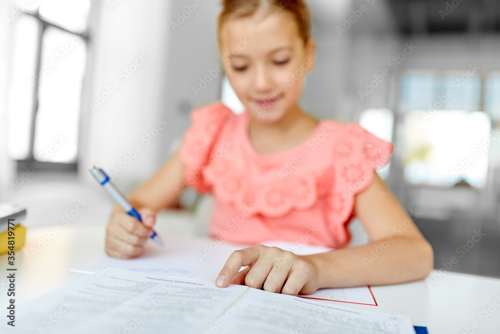 people, children, education and learning concept - close up of happy student girl with book writing to notebook at home people, children, education and learning concept - close up of happy student girl with book writing to notebook at home