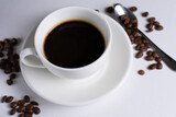 black coffee in a white mug with coffee beans on a white background