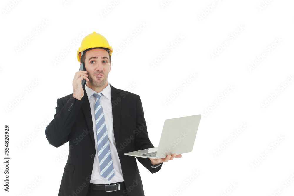 Handsome and smart engineer in black suit Wearing a yellow safety engineerking hat with hand holding labtop and call in mobile for work isolated on yellow background. Copy Space Handsome and smart engineer in black suit Wearing a yellow safety engineerking hat with hand holding labtop and call in mobile for work isolated on yellow background. Copy Space