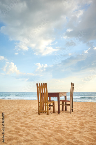 Wooden table and two chairs on a beach.