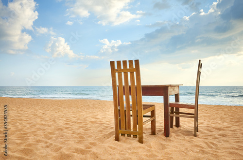 Wooden table and two chairs on a beach.