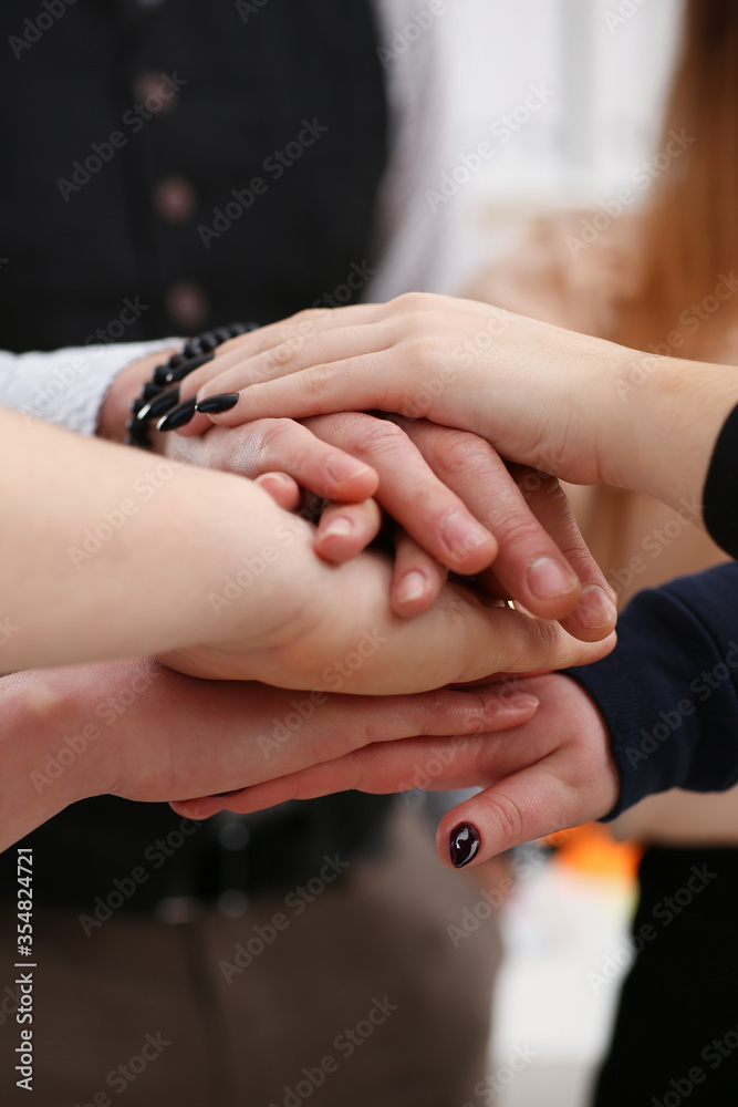 Group of people in suits crossed hands in pile for win