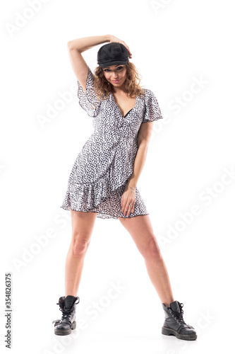 Stylish young woman posing relaxed holding cap or hat with dotted dress and leather ankle boots. Full body length isolated on white background.