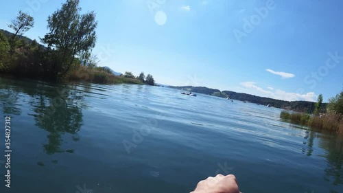 Stand up paddleboarding on the river Linth and lake of Zurich in Switzerland on a clam blue day. POV photo