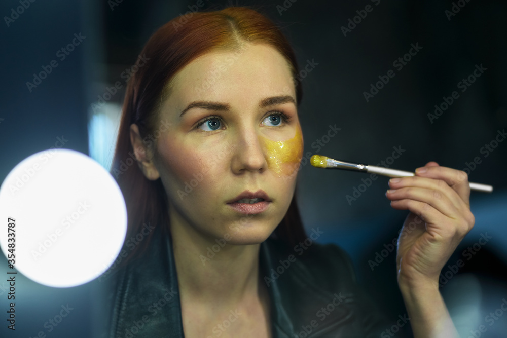 Obraz premium Beauty portrait of red head woman with gold mask on face. Skincare cleansing eco organic cosmetic