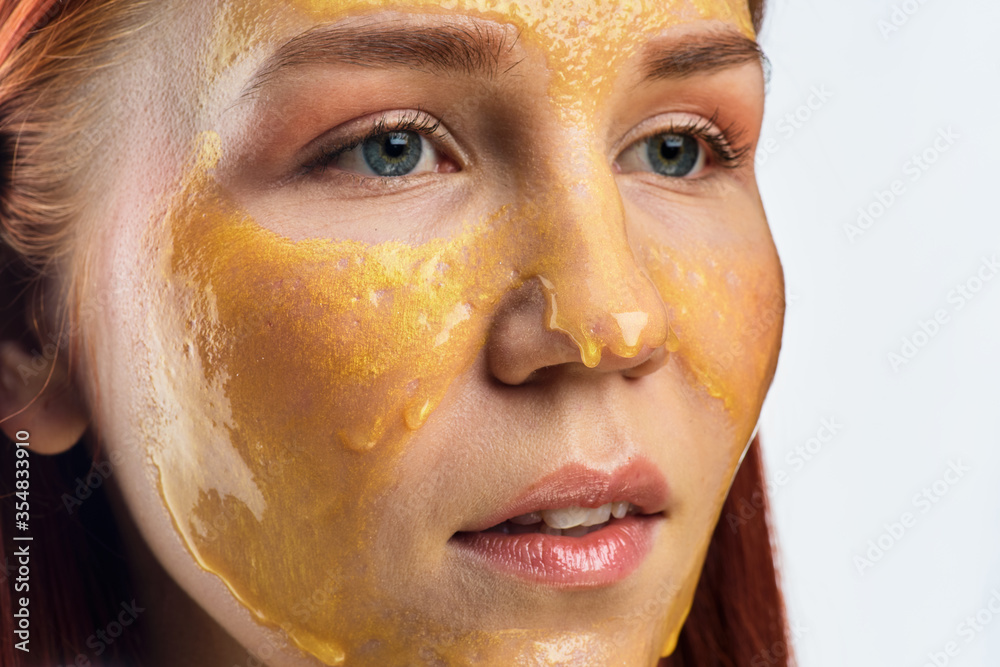 Beauty portrait of red head woman with gold mask on face. Skincare cleansing eco organic cosmetic