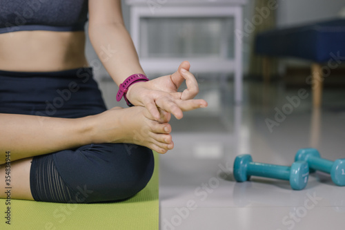 International Day of Yoga concept Asian woman doing meditation for yoga athlete sitting on an exercise mat at home