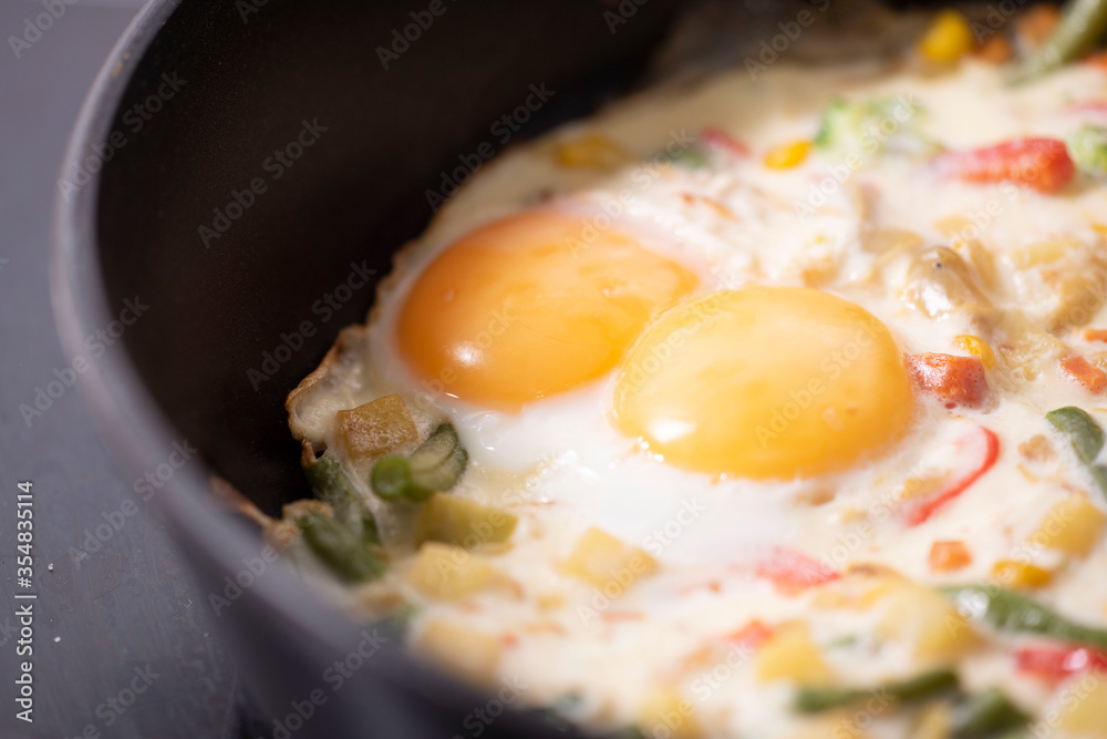 In a black pan, appetizer omelet fried eggs with fresh vegetables. In a black pan, appetizer omelet fried eggs with fresh vegetables.