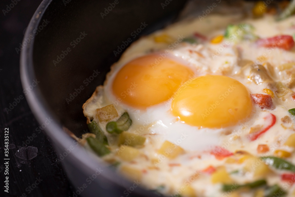 In a black pan, appetizer omelet fried eggs with fresh vegetables. In a black pan, appetizer omelet fried eggs with fresh vegetables.