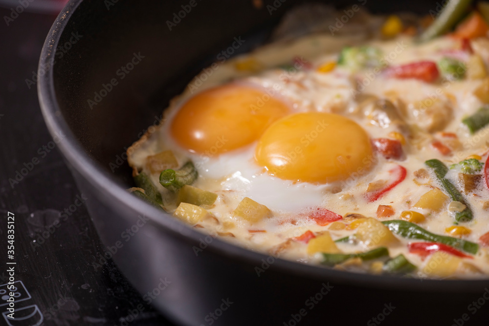 In a black pan, appetizer omelet fried eggs with fresh vegetables. In a black pan, appetizer omelet fried eggs with fresh vegetables.