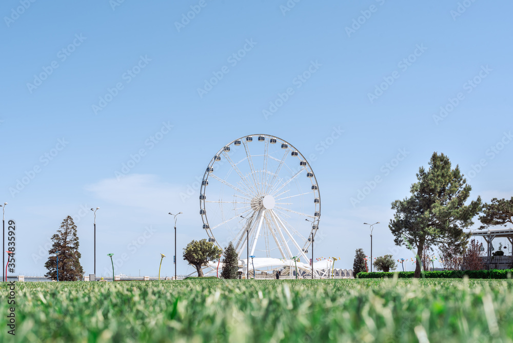 white Ferris wheel with green grass and trees in Baku, Azerbaijan