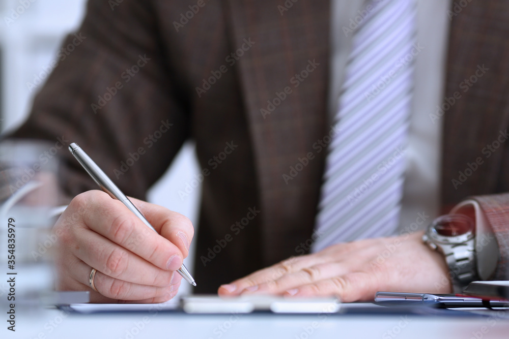 Male arm in suit and tie hold silver pen Male arm in suit and tie hold silver pen