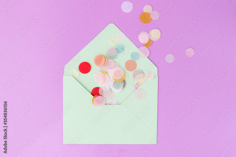 The envelope of mint color with colorful confetti on a violet background. Flat lay. Festive concept.
