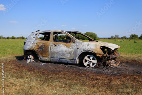 Burnt out car in field. Stolen car dumped in agricultural area photo