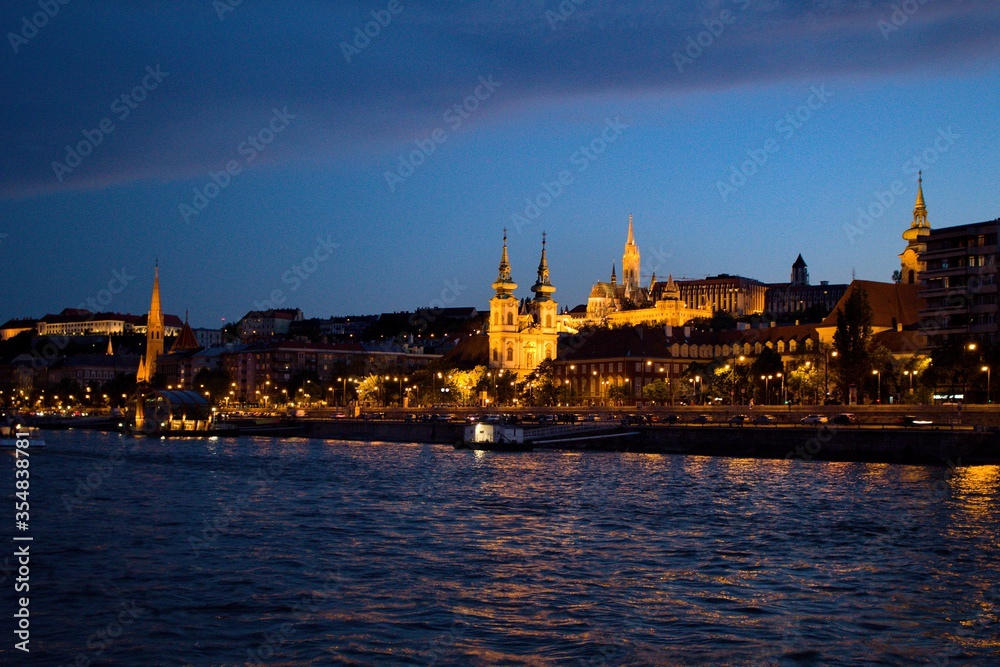 Landscape view of Szilágyi Dezső Square Reformed Church and the castle on the Dunabe river in Budapest, Hungary during sundown
