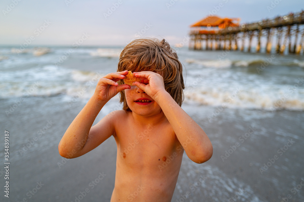 Boy playing on the beach on summer holidays. Cute boy having fun on a summer vacation in the sea. Sea vacation for family.