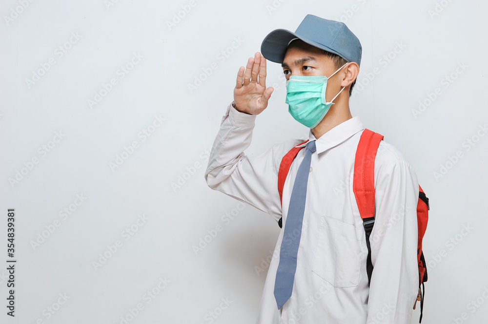 Indonesian Senior student of senior high school in Indonesian wearing protection face mask with school uniform giving salute